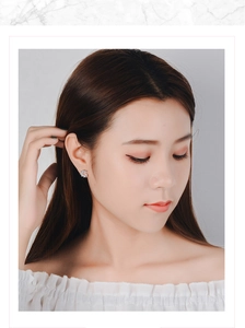 Close-up of minimalist windmill zircon stud earrings worn on a model's earlobe