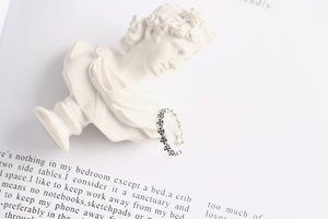 Detailed view of an open silver ring with clover hollow patterns on a white statue