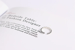 Macro detail of silver vintage cross pattern ring placed on an open fashion book