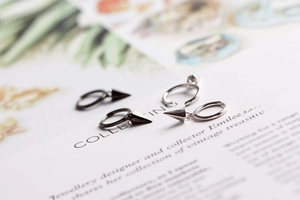 Detailed macro view of S925 sterling silver geometric hoop earrings with conical pendants