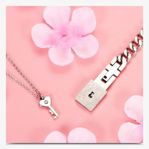 Detail of silver couple lock bracelet and key necklace set with pink petals background