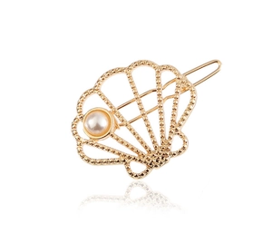 Detail of golden hollow shell hair clip with a pearl accent on white background