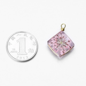 Handmade diamond-shaped resin pendant with pink dried flowers and golden wire wrapping