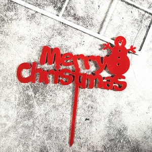 Macro view of red acrylic Merry Christmas cake topper with snowman detail for party decor