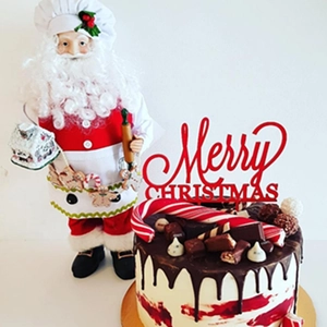 Macro detail of red Merry Christmas acrylic cake topper on a chocolate dessert