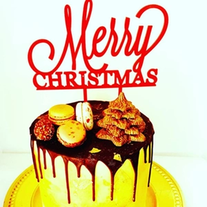 Close-up of red acrylic Merry Christmas topper on a chocolate and macaron dessert