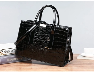 Macro view of black crocodile pattern leather tote with silver metal clasp and handles