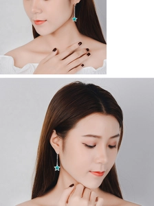 Detail showing long silver star earrings with turquoise stones on a model