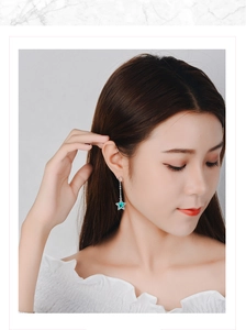 Close-up of elegant long star earrings in silver with blue charms on a female model