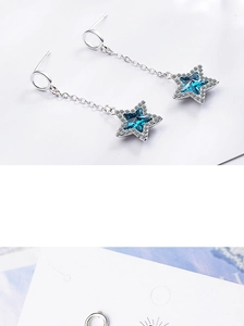 Close-up of silver star earrings featuring deep blue crystals and micro-pave diamond details