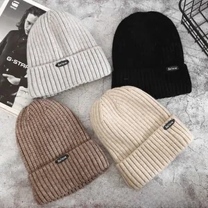 Detail view of four minimalist knit beanies in grey, black, coffee, and beige colors