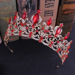 Close-up of golden Baroque crown with large red gemstones and shimmering clear rhinestones