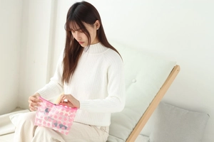 Close-up of a pink polka dot transparent PVC makeup bag held by a person in a bright room