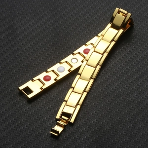 Macro detail of gold magnetic bracelet with red and white stones on carbon fiber background