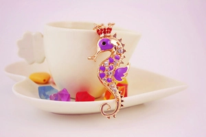 Detailed close-up of a seahorse keychain featuring purple enamel and sparkling crystals
