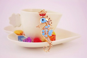 Detail of colorful seahorse keychain with blue enamel and rhinestones on a white plate