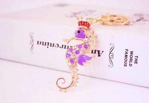 Detailed close-up of a golden seahorse keychain with purple enamel and sparkling rhinestones