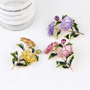 Detailed view of three colorful enamel flower brooches in purple, orange, and pink colors