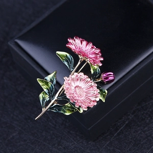 Detail shot of a floral enamel brooch with pink chrysanthemum flowers on a black case