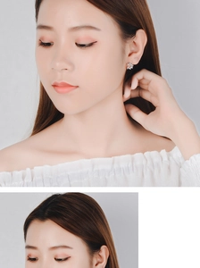 Close-up of sparkling silver windmill earrings with zircon stones on a model ear