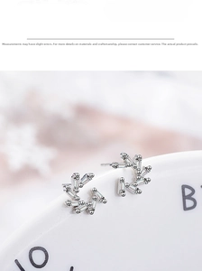 Detailed view of silver zircon wreath earrings with baguette crystals on a ceramic plate