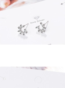 Macro shot of silver zircon windmill stud earrings with geometric radiating patterns