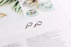 Macro shot of silver S925 sterling silver huggie earrings with sharp cone-shaped pendants