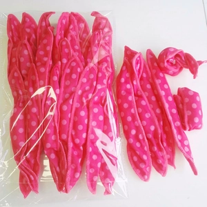 Detailed view of pink polka dot sponge hair rollers in bulk packaging and usage display
