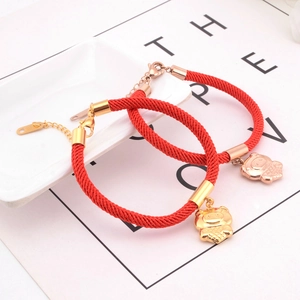 Close-up of red braided rope bracelets with golden pig charms and zodiac details