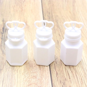 Three white heart-top plastic bubble bottles for wedding decor on a wooden surface