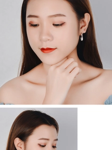 Detail of silver star dangle earrings worn by a model against a light gray background
