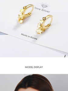 Detail view showing gold star dangle earrings on display card and model's ear