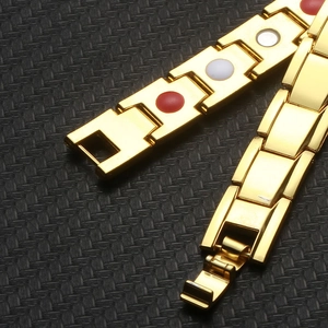 Detail of gold-plated magnetic health bracelet with red and white stone inlays and clasp