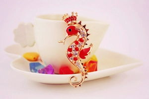 Detail view of golden seahorse keychain with red enamel and clear rhinestones on ceramic