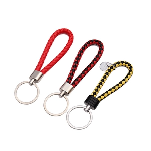 Tre portachiavi in pelle intrecciata nei colori rosso, nero-rosso e giallo-nero su bianco