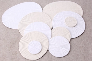 Stack of handmade round and oval cotton rope woven heat-resistant coasters and placemats