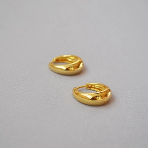 Detailaufnahme goldener Tropfenohrringe mit hochglänzender metallischer Oberfläche
