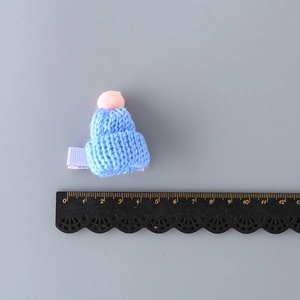 Mini blue knitted hat hair clip with pink pompom and size scale reference measurement