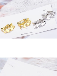 Detail of star-shaped pendant hoop earrings in gold and silver finish with feathers
