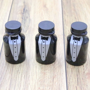 Three black tuxedo-style bubble bottles with white bow tie details on a wooden surface