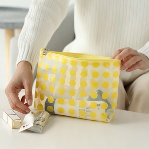 Transparent PVC makeup bag with yellow polka dots and zipper closure in a home setting