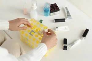 Waterproof clear PVC makeup bag with yellow polka dots being filled with cosmetics