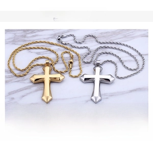 Close-up of gold and silver stainless steel cross pendants with rope chains on marble