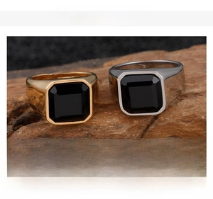 Polished stainless steel men's signet rings with black stones on a wood base