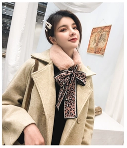 Detail of pink faux fur neck warmer with leopard print silk ribbon on beige coat