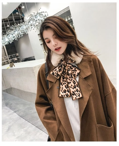 Detail of leopard print bow scarf with white faux fur trim on a brown wool coat