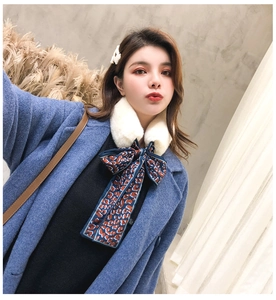 Detail of faux rabbit fur scarf with blue leopard print ribbon on a blue coat