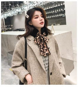 Detail of leopard print ribbon bow on black faux rabbit fur scarf collar with beige coat