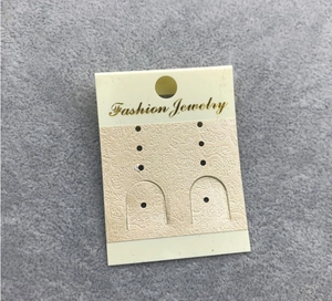 Close-up of beige paper jewelry display card with golden Fashion Jewelry text on felt