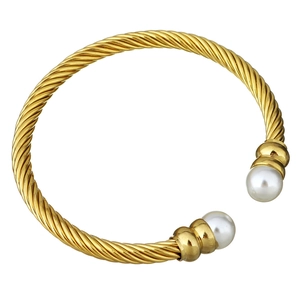 Close-up of golden cable twist bangle featuring elegant white pearls on both ends